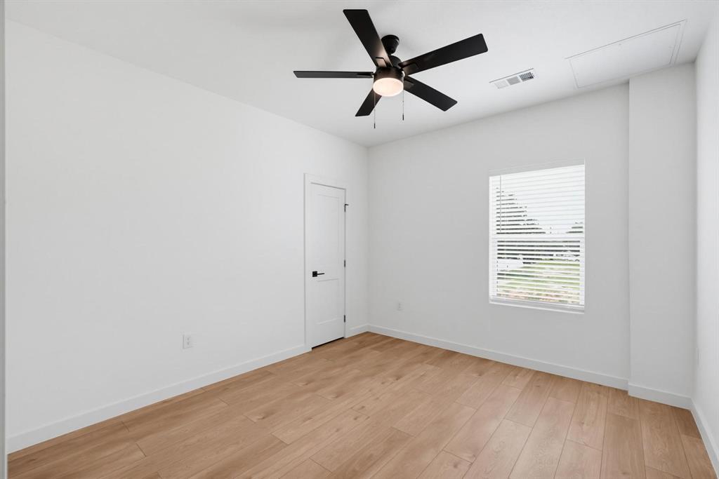 504 South O Connor Road Irving, TX 75060 - Photo 9 of 23 Spacious room featuring wood-finish flooring, a contemporary ceiling fan, crisp white walls, a single window with blinds, and a white door with black hardware