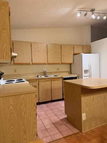 a kitchen with kitchen island granite countertop a sink and white cabinets