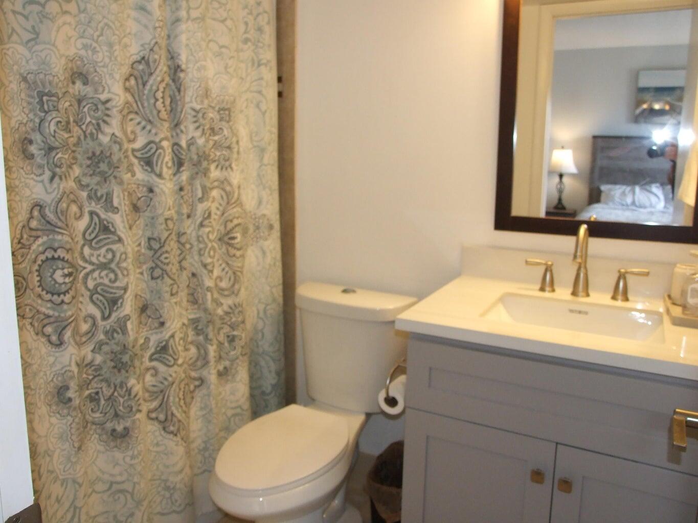 1605 Highway 1, Unit 203 V4 Jupiter, FL 33477 - Photo 23 of 33 a bathroom with a sink a toilet and a mirror