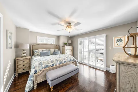 a bedroom with a bed a chandelier and a dresser next to a window
