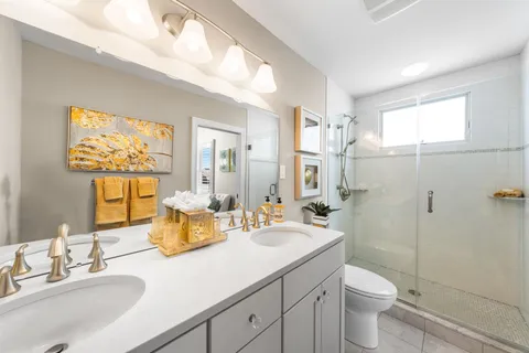 a bathroom with a double vanity sink toilet and a mirror
