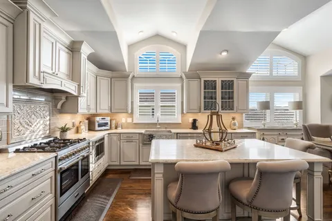 a kitchen with stainless steel appliances granite countertop a stove a sink a oven a dining table and chairs