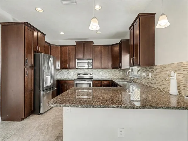 a kitchen with stainless steel appliances granite countertop a refrigerator a stove a sink and a microwave