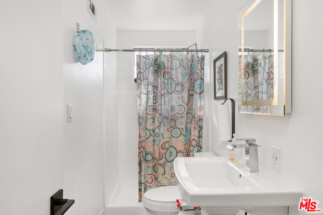 1397 Sycamore Drive Simi Valley, CA 93065 - Photo 14 of 20 a bathroom with a shower curtain and a sink