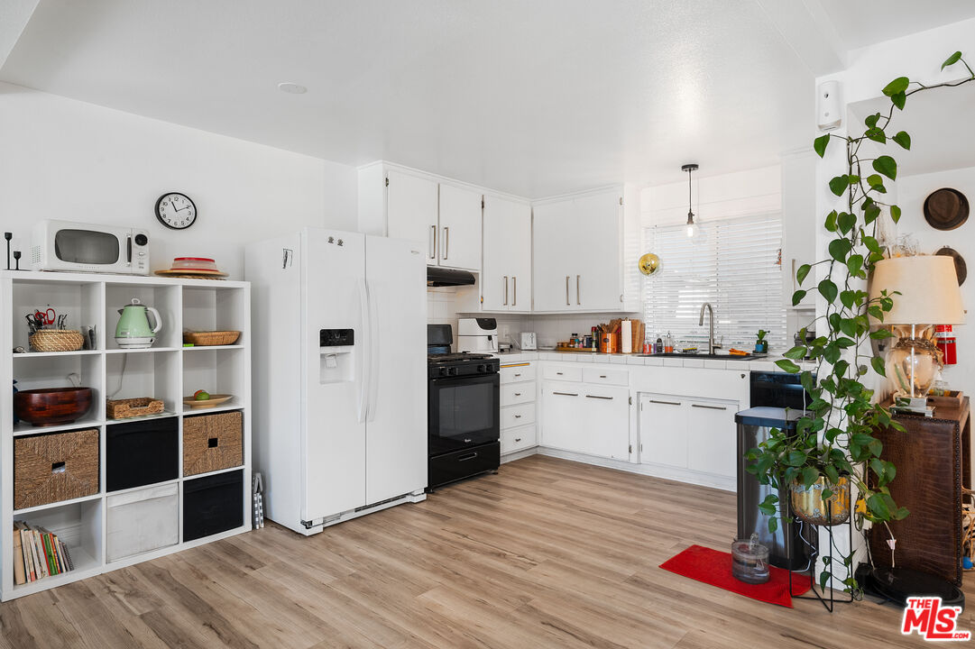 1397 Sycamore Drive Simi Valley, CA 93065 - Photo 6 of 20 a open kitchen with white cabinets and wooden floor