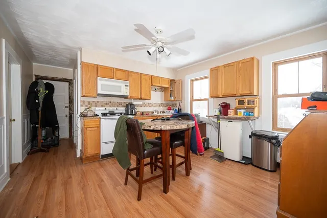 a open kitchen with stainless steel appliances granite countertop a stove top oven a refrigerator a dining table and chairs with wooden floor