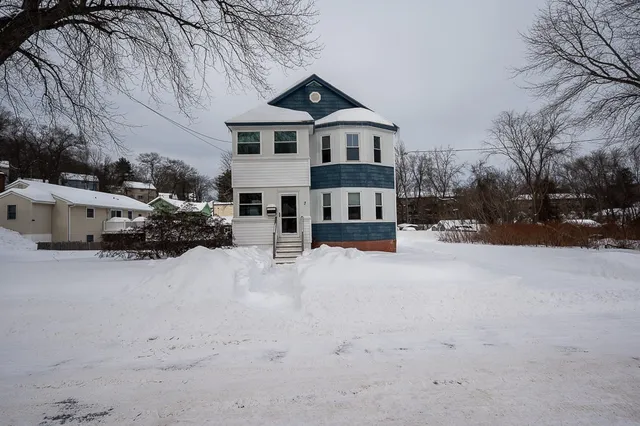 a front view of a house with a yard covered in snow