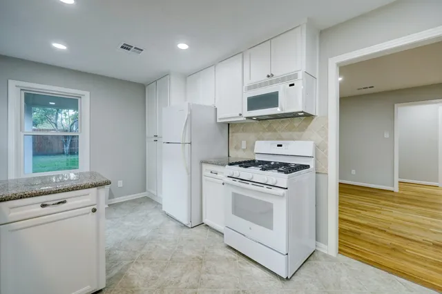 a kitchen with white cabinets and white appliances