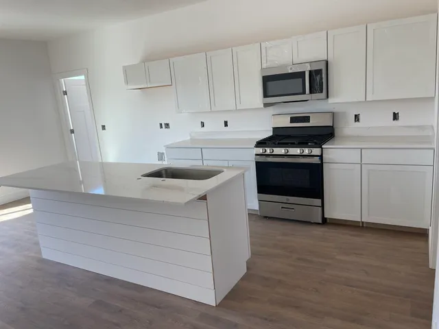 a kitchen with stainless steel appliances granite countertop a sink stove and microwave
