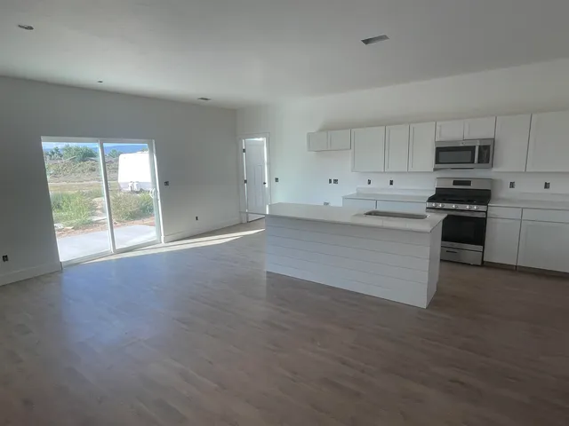 a view of a kitchen with stainless steel appliances a stove top oven