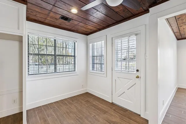 a view of an empty room with wooden floor and a window