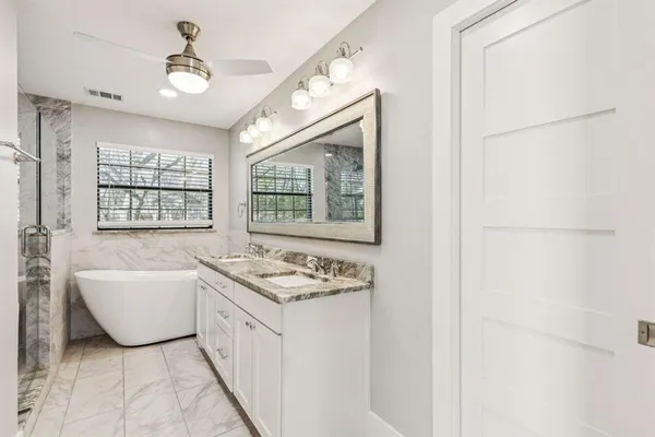 a bathroom with a granite countertop sink a mirror and a shower