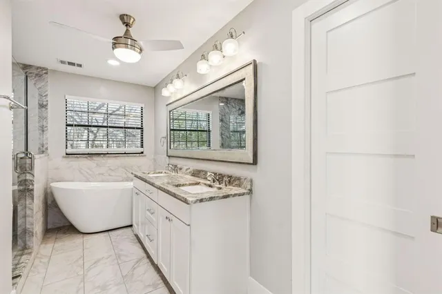 a bathroom with a granite countertop sink a mirror and a shower