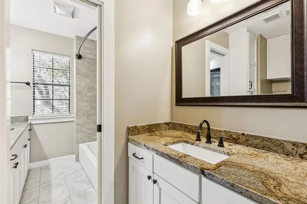 a bathroom with a granite countertop sink a mirror and a shower