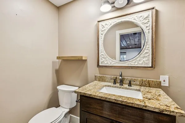 a bathroom with a granite countertop toilet sink and mirror
