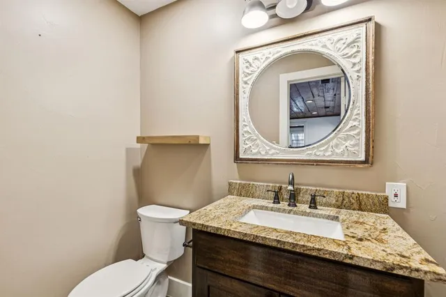a bathroom with a granite countertop toilet sink and mirror