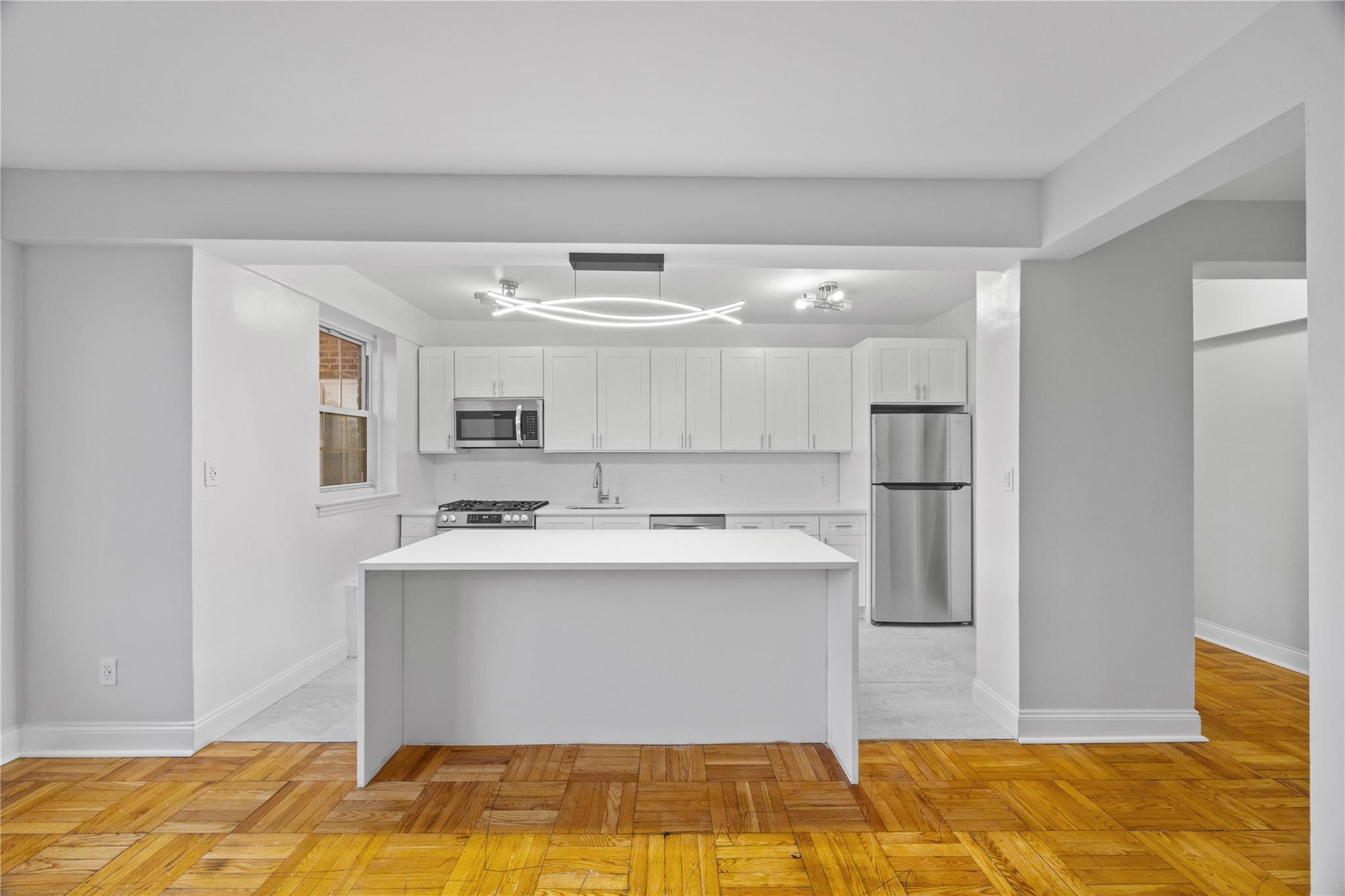 220 Pelham Road, Unit 4P New Rochelle, NY 10805 - Photo 1 of 1 Kitchen featuring stainless steel appliances, white cabinets, light countertops, and a kitchen island