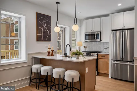 a kitchen with stainless steel appliances granite countertop a refrigerator a sink a stove a dining table and chairs