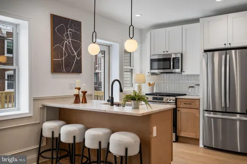 a kitchen with stainless steel appliances granite countertop a sink a stove a refrigerator cabinets and chairs