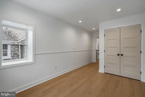 an empty room with wooden floor cabinet and windows