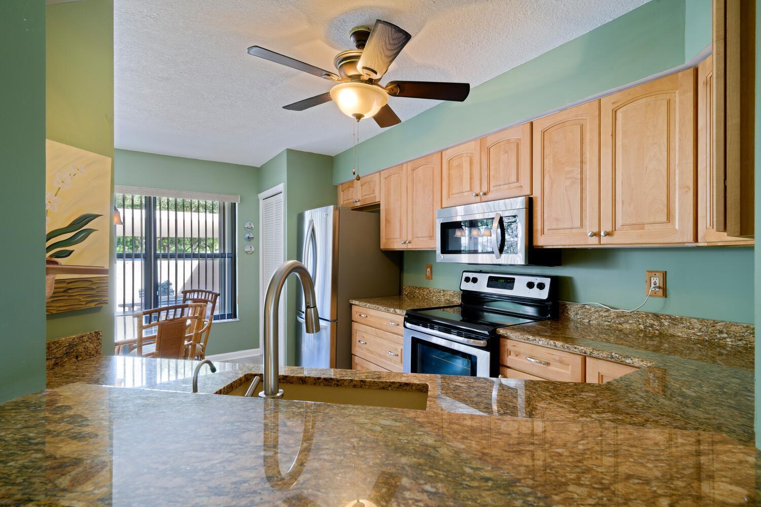 6030 Southeast Martinique Drive, Unit 102 Stuart, FL 34997 - Photo 11 of 31 a kitchen with stainless steel appliances granite countertop a stove top oven a sink a dining table and chairs with wooden floor