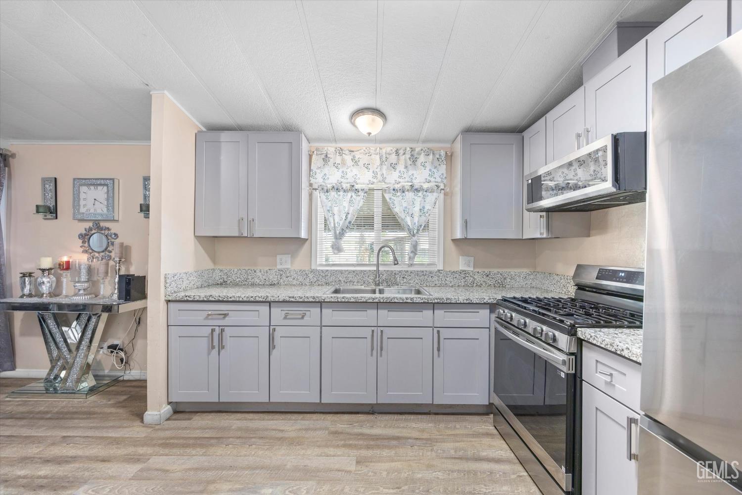 Undisclosed Address Delano, CA 93215 - Photo 16 of 43 a kitchen with stainless steel appliances granite countertop a stove a sink and a microwave