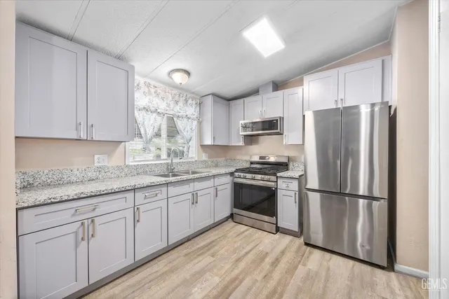 a kitchen with granite countertop white cabinets stainless steel appliances and a sink
