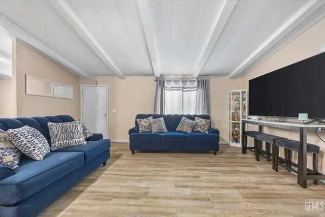 a living room with couches and a flat screen tv with kitchen view