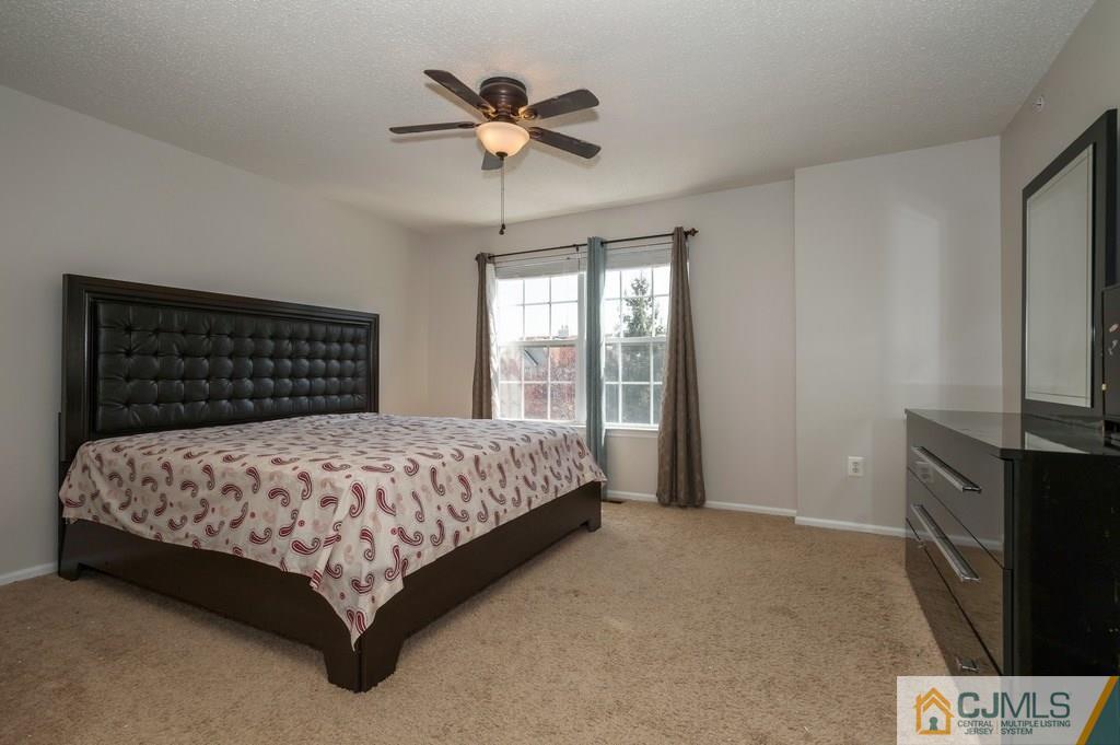 85 Prestwick Way, Unit 85 Edison, NJ 08820 - Photo 8 of 18 a bedroom with a bed chandelier and a flat tv screen