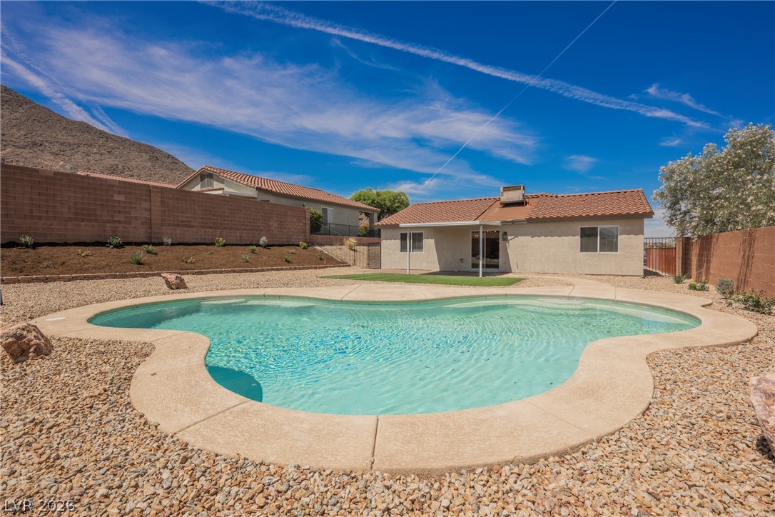 112 Iridescent Street Henderson, NV 89012 - Photo 18 of 24 A sparkling pool awaits in this desert backyard, framed by a clear blue sky and distant hills.