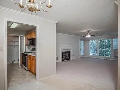 an empty room with a fireplace chandelier and windows