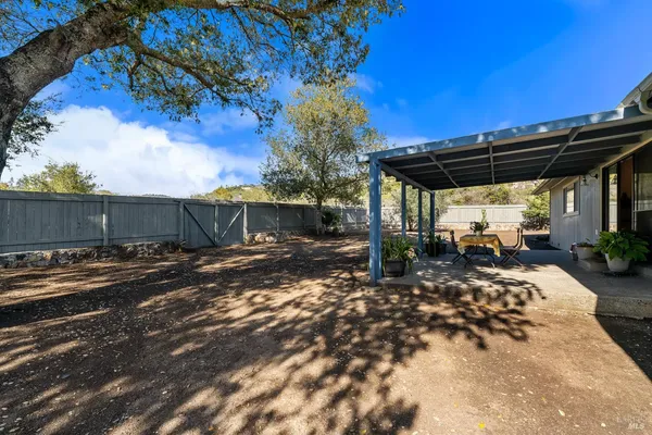a view of a backyard with table and chairs under an umbrella with wooden fence