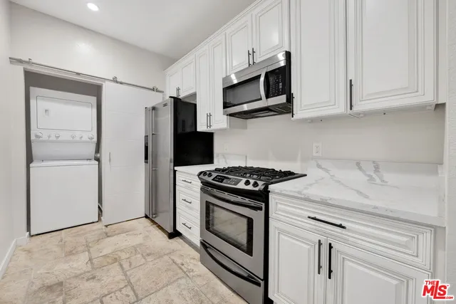 a kitchen with stainless steel appliances granite countertop white cabinets and a stove