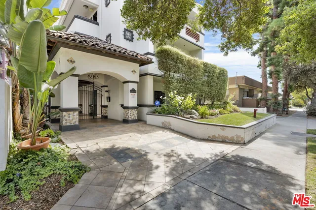 a view of a white house with a yard and potted plants