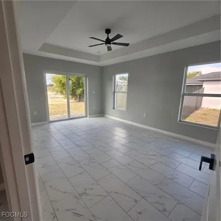 a view of an empty room and window and ceiling fan