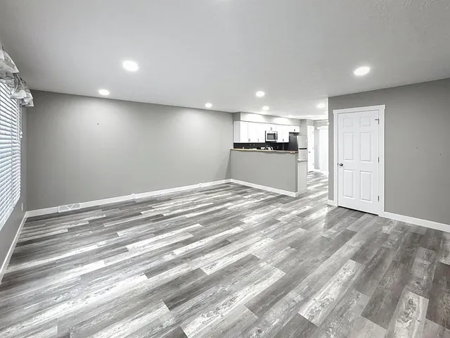 a view of kitchen and empty room with wooden floor