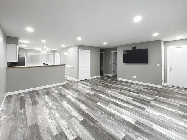 a view of an empty room with kitchen and a window