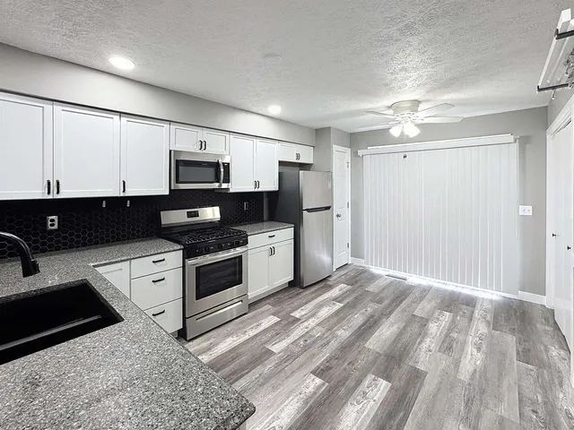 a kitchen with stainless steel appliances a stove a sink and white cabinets