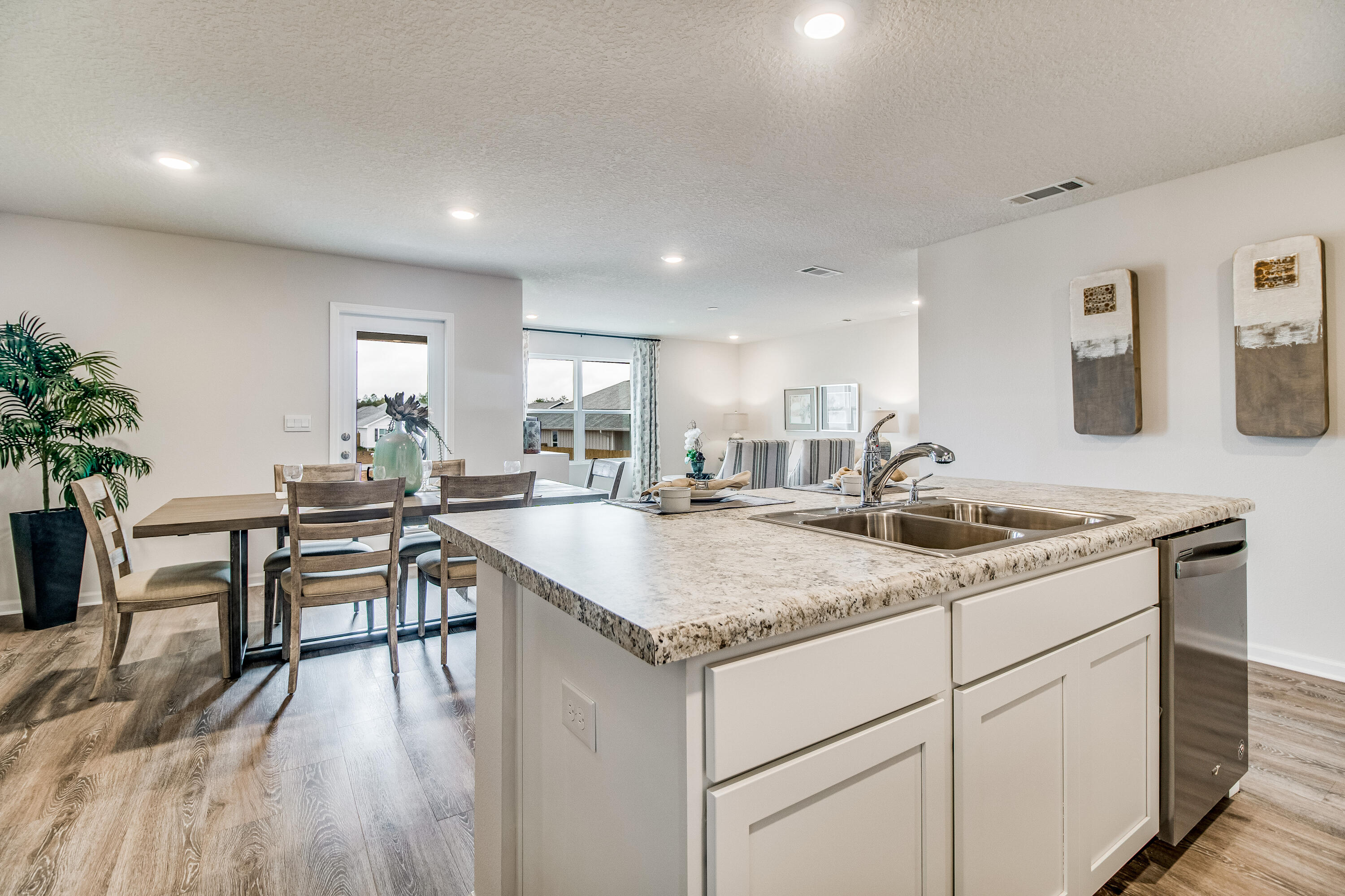 6324 Firefly Drive Milton, FL 32583 - Photo 7 of 32 a kitchen with a stove a sink a dining table and chairs with wooden floor