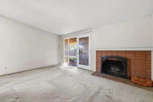 a view of an empty room with a fireplace and a window