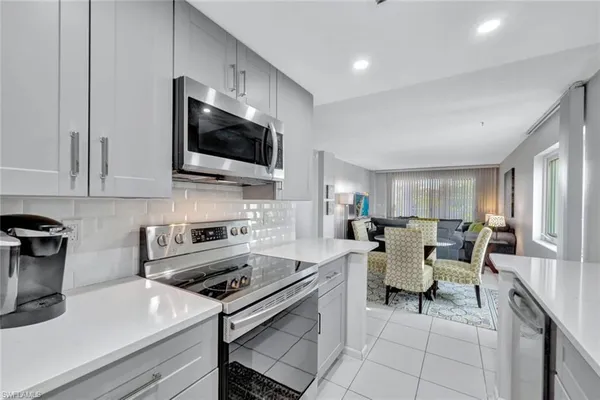 a living room with furniture a flat screen tv and kitchen view
