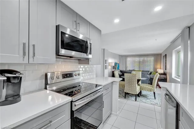 a living room with furniture a flat screen tv and kitchen view