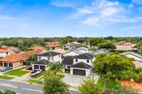 an aerial view of residential houses with outdoor space and trees