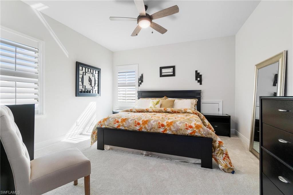 8936 Mustique Lane Naples, FL 34114 - Photo 17 of 29 a bed sitting in a bedroom next to a window with pc on the dresser