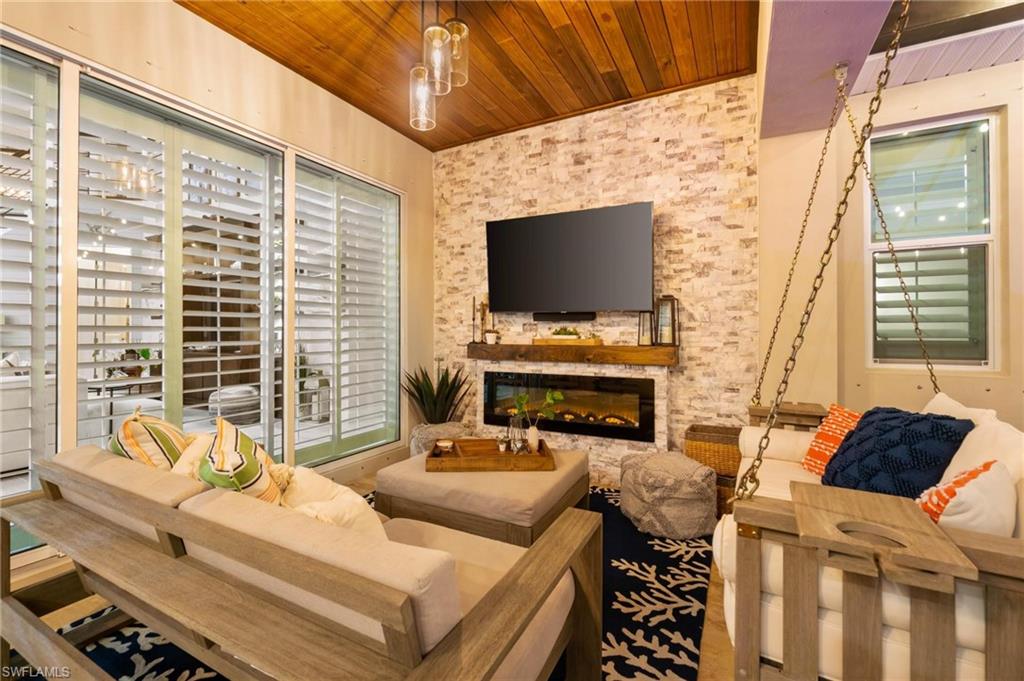 8936 Mustique Lane Naples, FL 34114 - Photo 25 of 29 a living room with furniture a flat screen tv and a floor to ceiling window