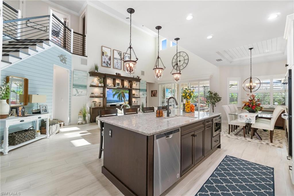 8936 Mustique Lane Naples, FL 34114 - Photo 7 of 29 a view of a kitchen with kitchen island stainless steel appliances a table chairs sink and wooden floor