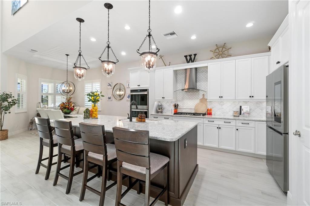8936 Mustique Lane Naples, FL 34114 - Photo 8 of 29 a kitchen with stainless steel appliances kitchen island granite countertop a sink and cabinets