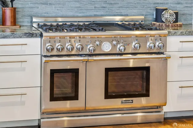 a large white kitchen with stainless steel appliances granite countertop a stove and cabinets
