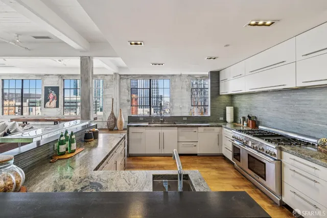a kitchen with granite countertop a stove and white cabinets