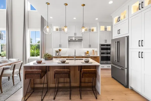 a kitchen with stainless steel appliances granite countertop a table chairs stove and refrigerator